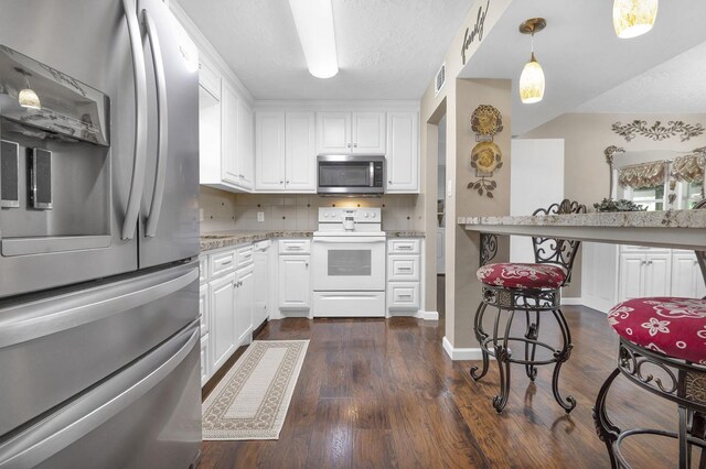 kitchen with white cabinetry, tasteful backsplash, dark hardwood / wood-style floors, decorative light fixtures, and appliances with stainless steel finishes