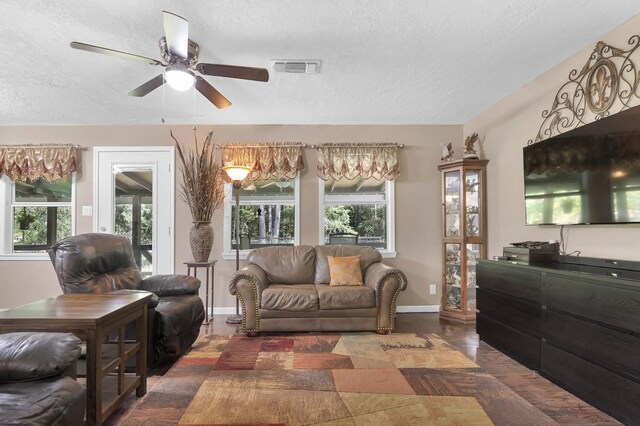 living room with ceiling fan and a textured ceiling