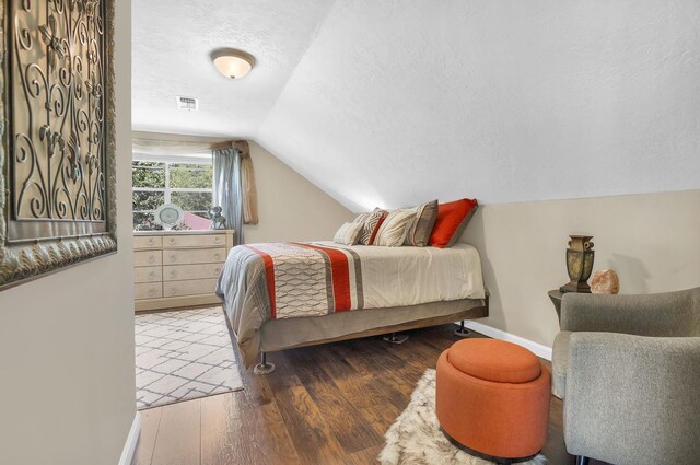 bedroom featuring hardwood / wood-style floors, a textured ceiling, and lofted ceiling