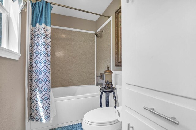 bathroom featuring shower / bath combination with curtain and toilet