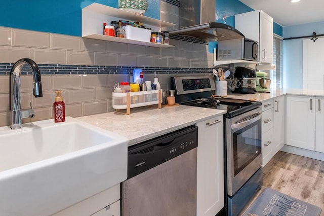 220 Casey Rd, Lufkin, TX 75901 - kitchen with stainless steel appliances, tasteful backsplash, white cabinetry, light wood-style flooring, and wall chimney range hood