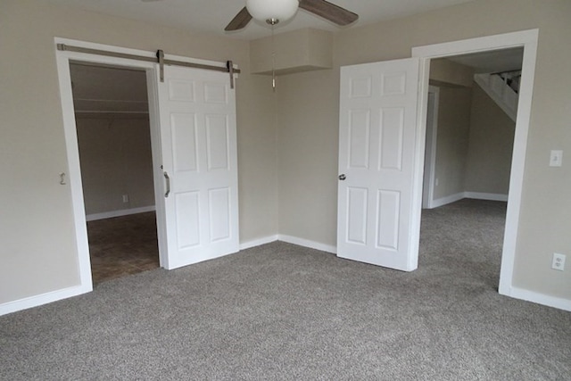 unfurnished bedroom featuring a walk in closet, a closet, carpet flooring, and baseboards