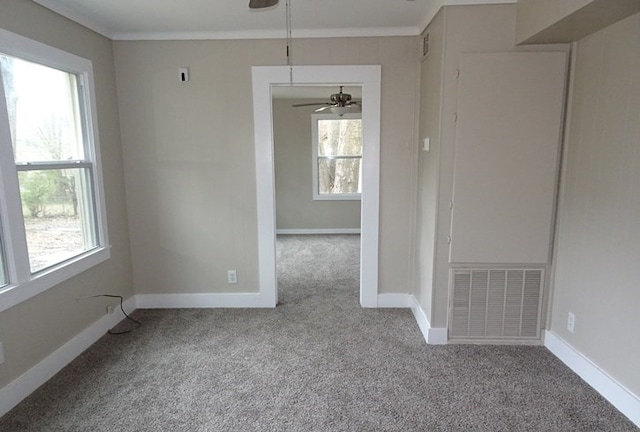 spare room with carpet, crown molding, visible vents, ceiling fan, and baseboards