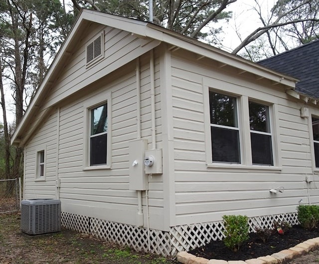 view of side of home with central AC, crawl space, and roof with shingles