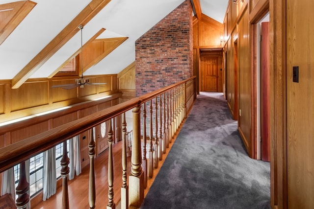 hall with vaulted ceiling with beams, wood walls, and carpet