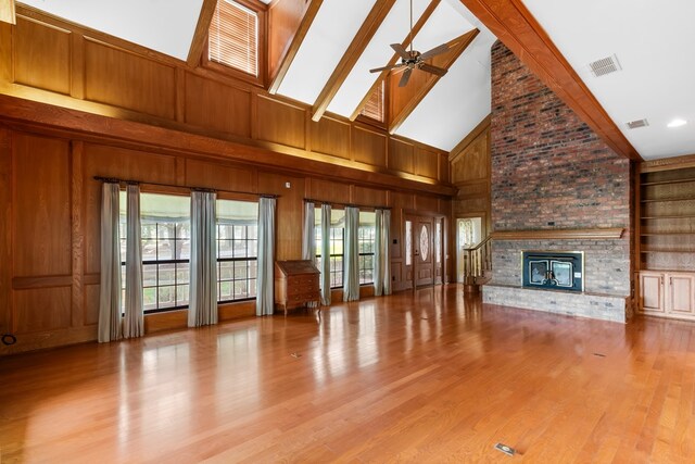 unfurnished living room featuring ceiling fan, light hardwood / wood-style floors, a fireplace, and high vaulted ceiling