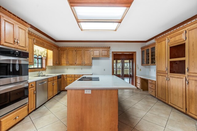 kitchen with sink, light tile patterned floors, ornamental molding, appliances with stainless steel finishes, and a kitchen island