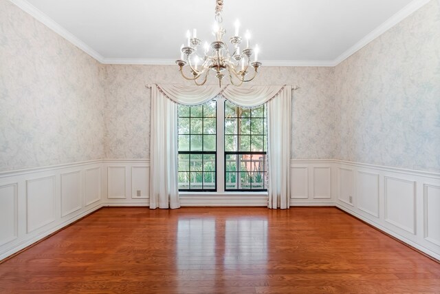 spare room with wood-type flooring, crown molding, and a notable chandelier