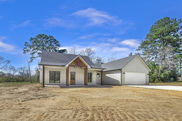 modern farmhouse with board and batten siding, driveway, a shingled roof, and an attached garage