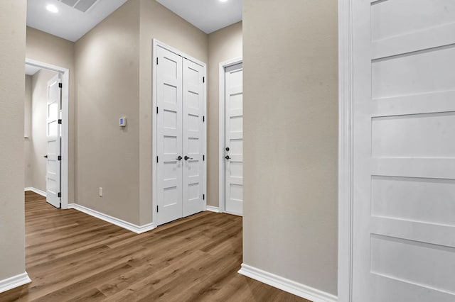 corridor with wood finished floors, visible vents, and baseboards