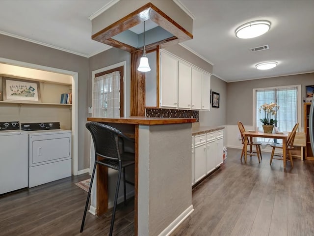 2600 Dogwood St, Nacogdoches, TX 75965 - kitchen featuring independent washer and dryer, white cabinetry, ornamental molding, dark wood-style floors, and tasteful backsplash