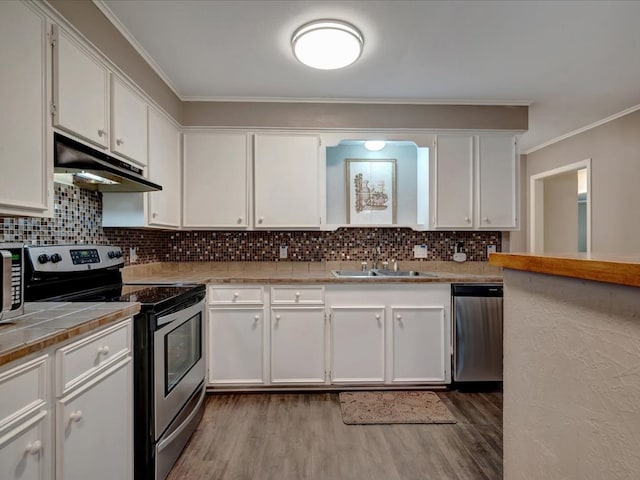 2600 Dogwood St, Nacogdoches, TX 75965 - kitchen with stainless steel appliances, under cabinet range hood, dark wood finished floors, ornamental molding, and white cabinetry
