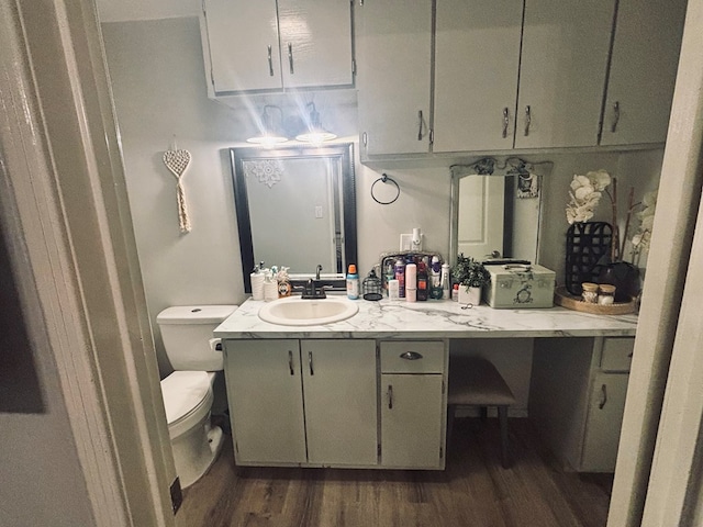 half bath with vanity, toilet, and wood finished floors