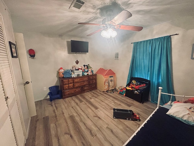 bedroom featuring light wood finished floors, visible vents, and a ceiling fan