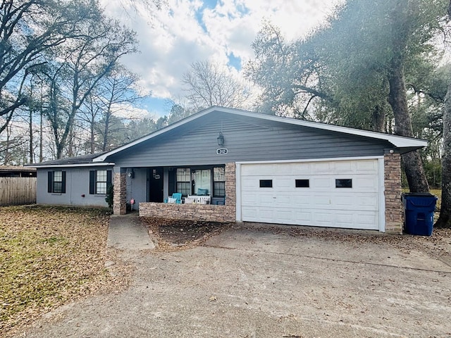 ranch-style house with concrete driveway, covered porch, fence, a garage, and stone siding