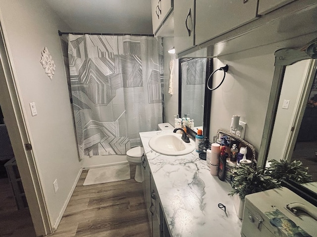 bathroom with baseboards, a shower with shower curtain, toilet, wood finished floors, and vanity