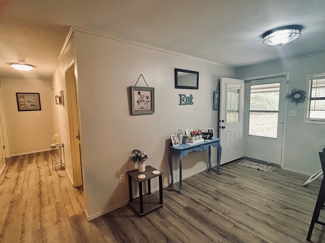 foyer entrance with crown molding, wood finished floors, and baseboards