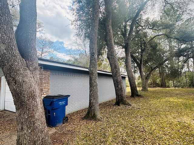 view of property exterior with brick siding and a yard