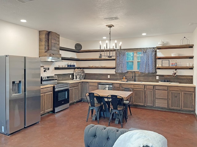 kitchen featuring an inviting chandelier, hanging light fixtures, stainless steel appliances, extractor fan, and a textured ceiling