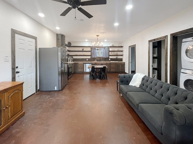 living room featuring stacked washer and dryer and ceiling fan with notable chandelier