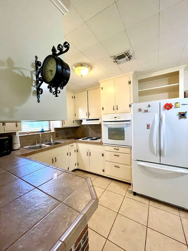 7203 Fm 326, Lufkin, TX 75901 - kitchen with white appliances, light tile patterned floors, under cabinet range hood, and white cabinetry
