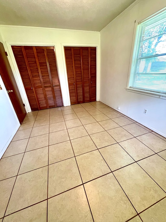 7203 Fm 326, Lufkin, TX 75901 - unfurnished bedroom with multiple closets, light tile patterned flooring, and a textured ceiling