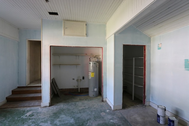 interior space featuring electric water heater, concrete flooring, and lofted ceiling