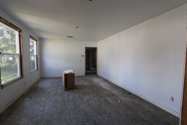 unfurnished room featuring dark wood-type flooring and a healthy amount of sunlight