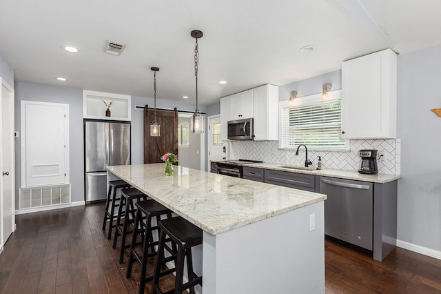 1402 Robinwood, Lufkin, TX 75904 - kitchen with appliances with stainless steel finishes, a sink, a center island, dark wood finished floors, and light stone counters