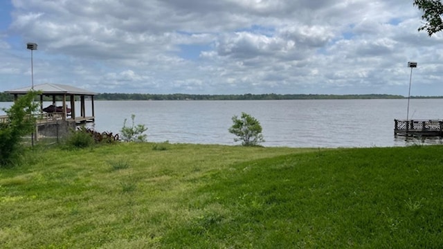 view of dock with a yard and a water view