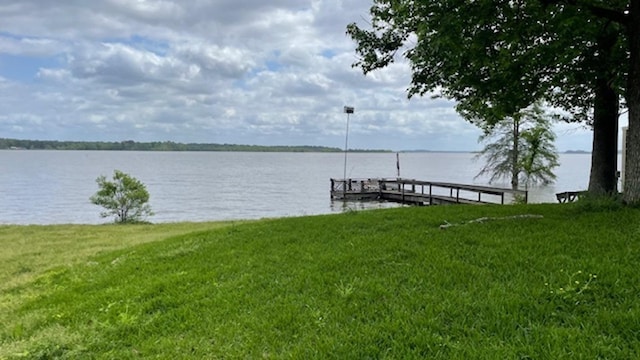 dock area with a lawn and a water view