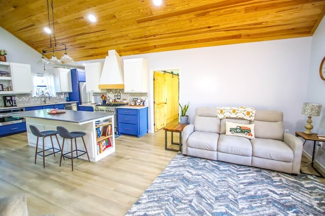 kitchen featuring light wood-type flooring, blue cabinets, white cabinets, a kitchen island, and a breakfast bar area
