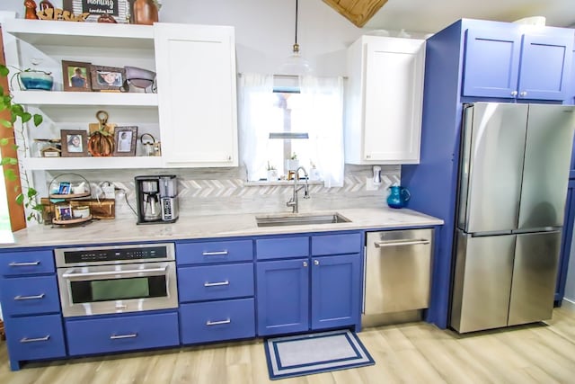 kitchen with sink, light hardwood / wood-style flooring, decorative light fixtures, white cabinetry, and stainless steel appliances