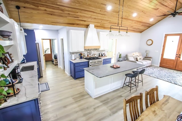 kitchen with lofted ceiling, blue cabinetry, decorative light fixtures, white cabinetry, and stainless steel appliances