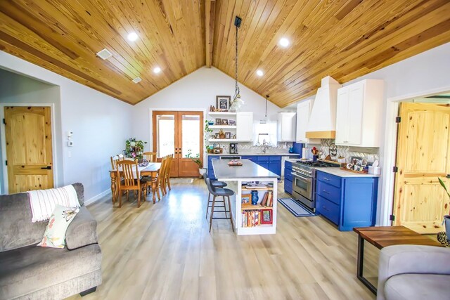 kitchen with blue cabinetry, high end stove, premium range hood, pendant lighting, and white cabinets