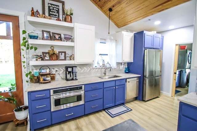 kitchen featuring sink, vaulted ceiling, decorative light fixtures, stacked washer / drying machine, and appliances with stainless steel finishes