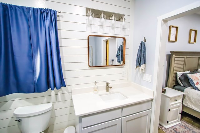 bathroom featuring vanity, wood walls, and toilet