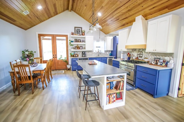 kitchen with a center island, white cabinets, hanging light fixtures, blue cabinetry, and stainless steel appliances