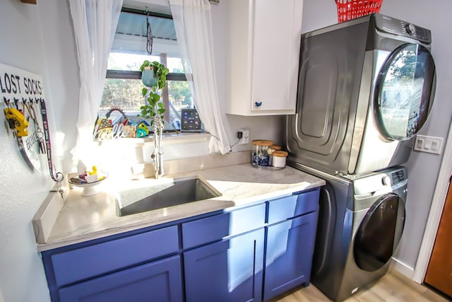 laundry room with stacked washer / dryer, sink, cabinets, and light wood-type flooring