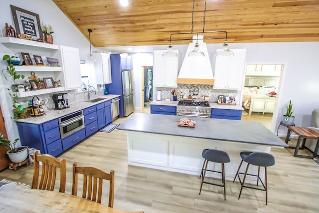 kitchen with appliances with stainless steel finishes, vaulted ceiling, sink, decorative light fixtures, and white cabinets