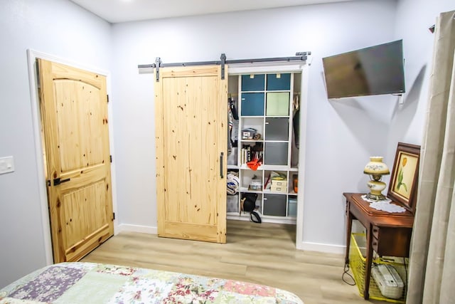 bedroom featuring a barn door and light hardwood / wood-style floors