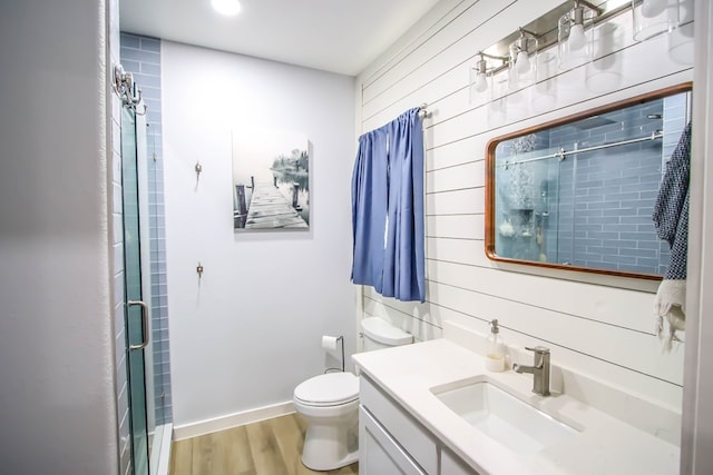 bathroom featuring wood walls, toilet, a shower with door, vanity, and hardwood / wood-style flooring