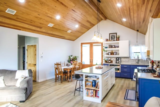 kitchen featuring blue cabinetry, a center island, light hardwood / wood-style flooring, decorative light fixtures, and white cabinets