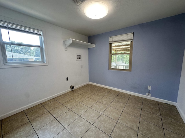 washroom with hookup for an electric dryer, light tile patterned floors, and hookup for a washing machine