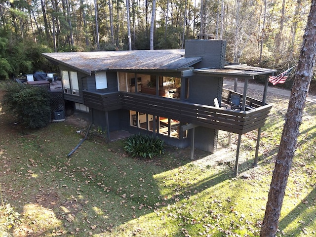 rear view of house featuring a lawn and a wooden deck