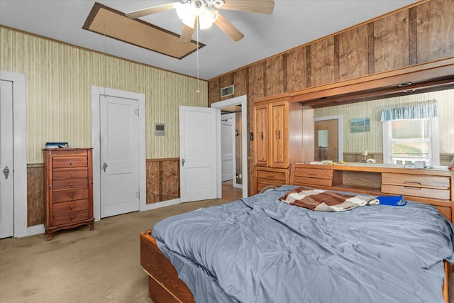 bedroom featuring light colored carpet, ceiling fan, and wooden walls