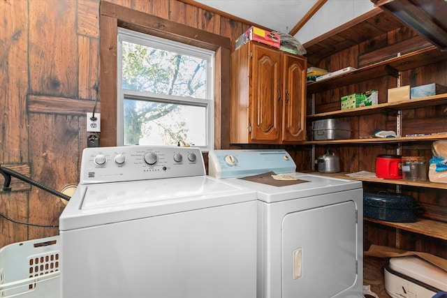 laundry area featuring cabinets, washer and clothes dryer, and wood walls