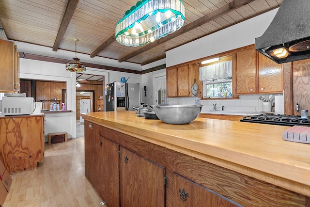 kitchen with beam ceiling, stainless steel fridge with ice dispenser, light hardwood / wood-style flooring, range hood, and decorative light fixtures