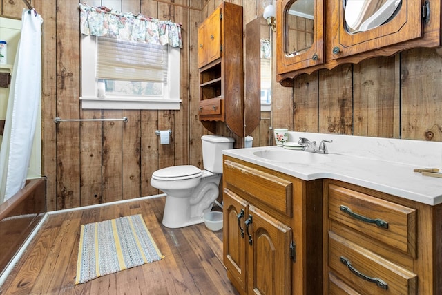 bathroom with wooden walls, vanity, wood-type flooring, and toilet