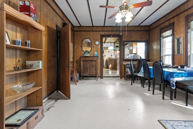 interior space featuring ceiling fan and wooden walls